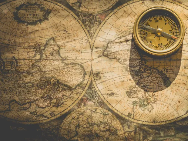 A brass compass resting on an old map